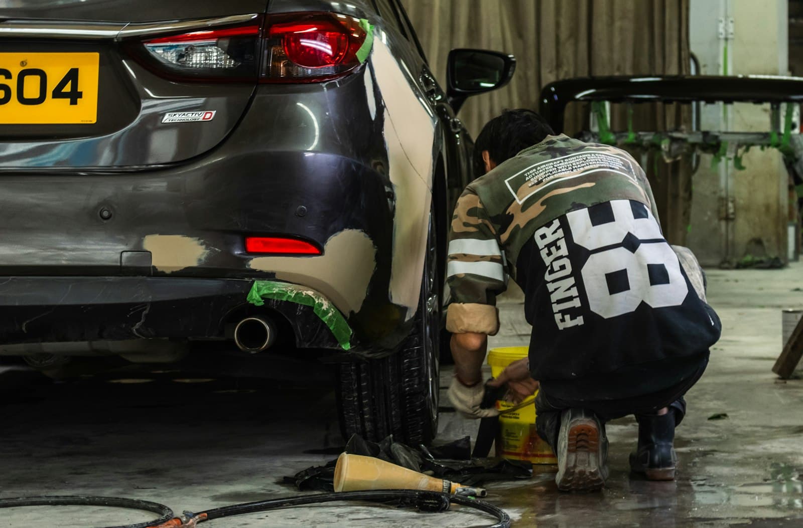 A technician repairing a body panel on a car in a workshop