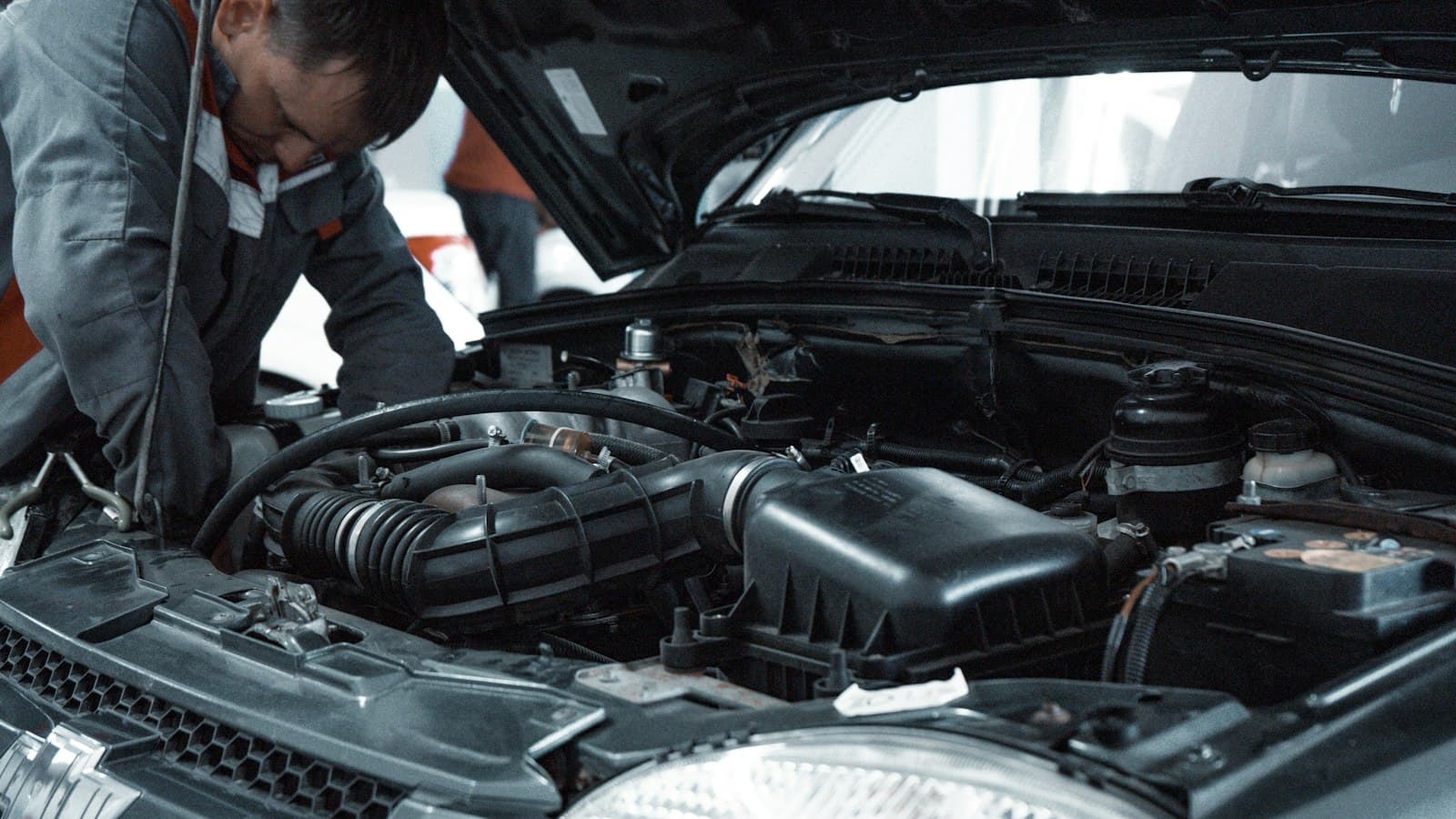 A technician leaning over a vehicle's engine bay to inspect it